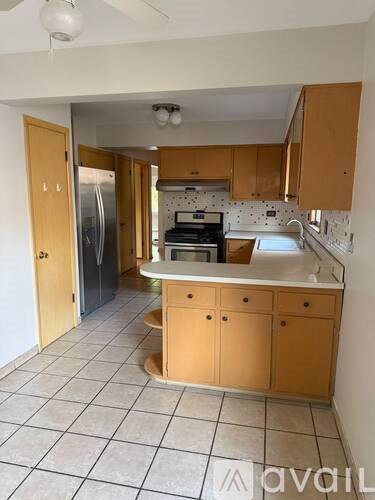 A kitchen with wooden cabinets and a tiled floor.