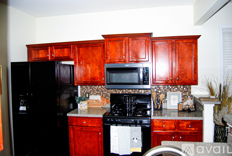 A kitchen with red cabinets and black appliances.
