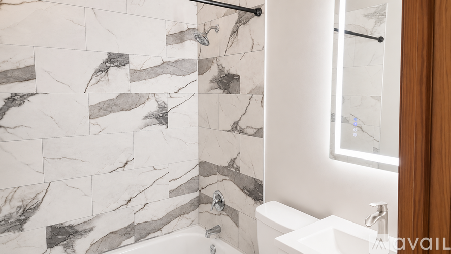 A bathroom with a marble tile shower and a white bathtub.