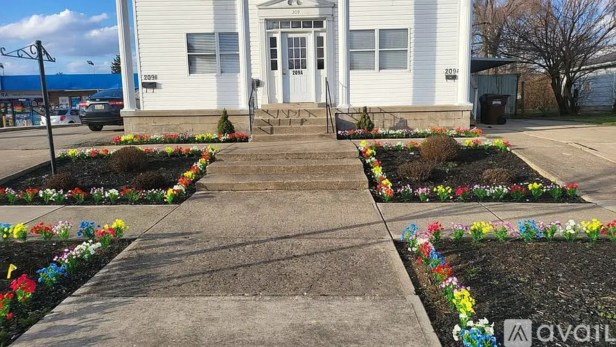 A white building with a flower bed in front of it.