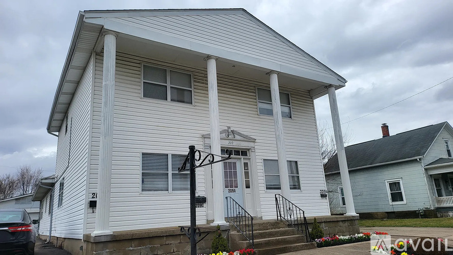 A white house with a porch and a sign that says "For Sale".