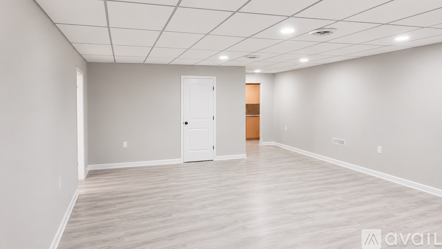 A spacious room with a door and a wall-mounted light fixture.