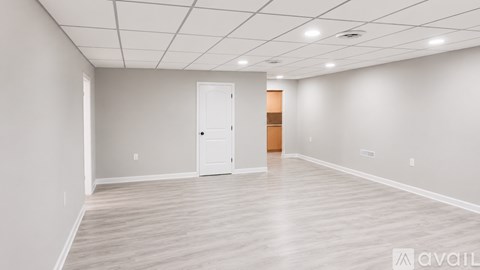 A spacious room with a door and a wall-mounted light fixture.
