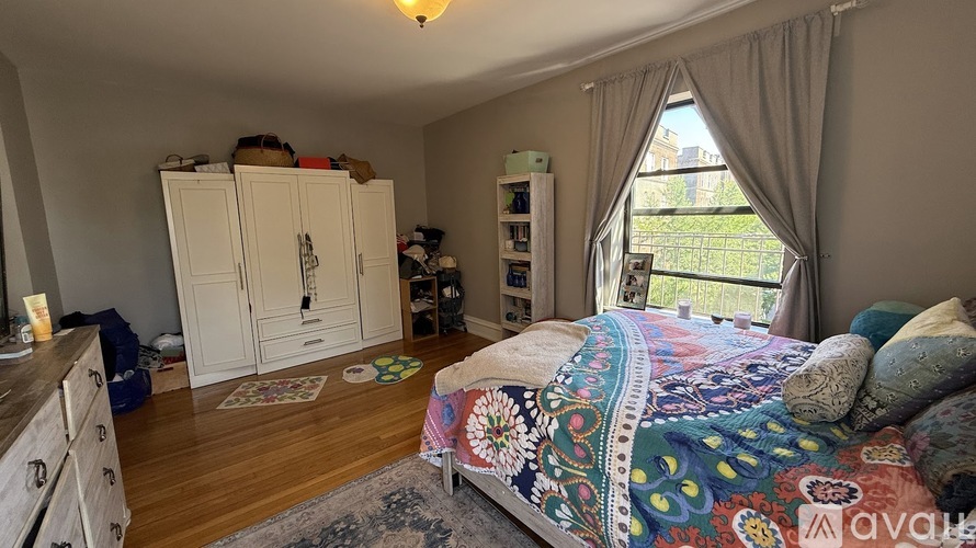 A bedroom with a bed, a dresser, and a window with curtains.