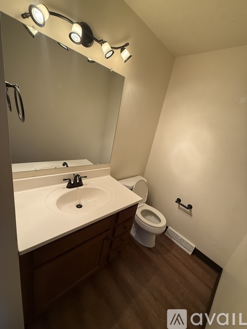A bathroom with a toilet, sink, and mirror.