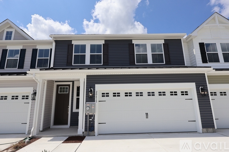 A two-story house with a black front door and white garage doors.