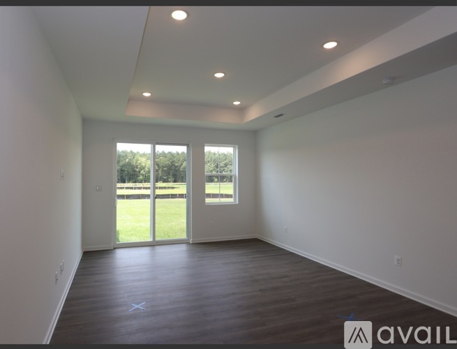 A room with a large window and sliding glass doors leading to a grassy area.