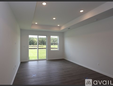 A room with a large window and sliding glass doors leading to a grassy area.