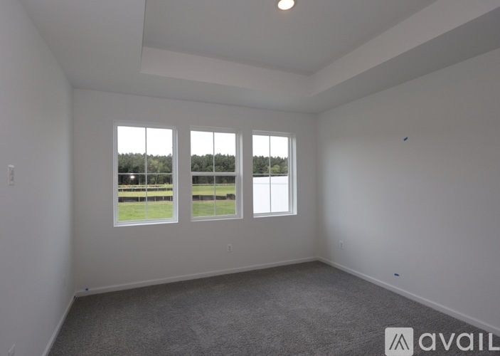 A spacious room with a large window overlooking a field.