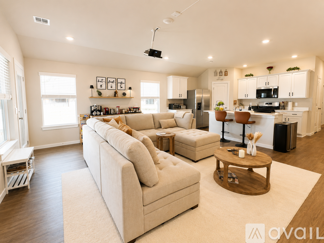 A modern living room with a large beige sofa and a kitchen area in the background.