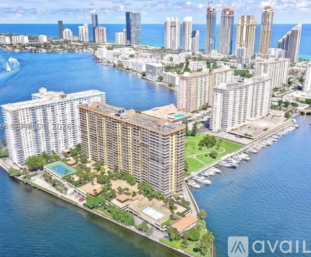 A large building with a pool in front of it is situated on a peninsula with a body of water on three sides.