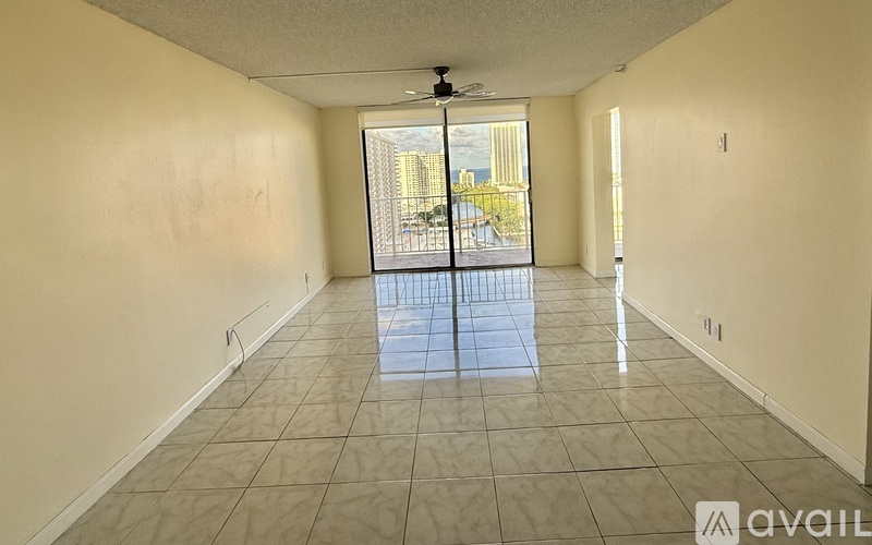 A spacious room with a fan and a view of a cityscape through a glass door.