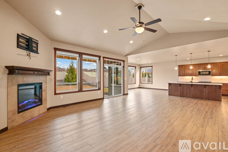A spacious living room with a fireplace and a ceiling fan.