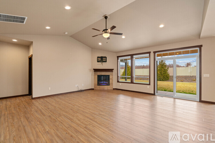 A spacious room with wooden floors and a ceiling fan.