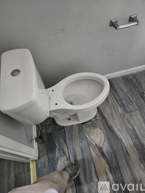 A toilet with a white tank and a white bowl is installed in a bathroom with a grey floor.