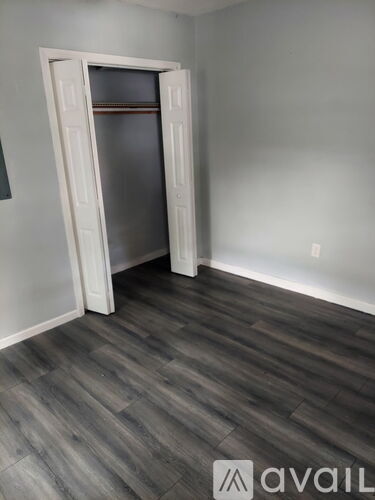 A room with a white door and wooden flooring.