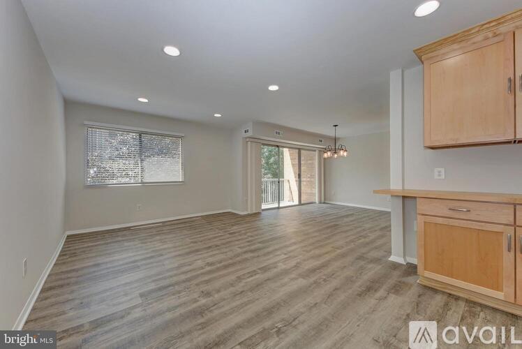 A spacious room with wooden flooring and a kitchen area with cabinets and a counter.