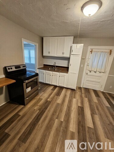 A kitchen with white cabinets and a wooden floor.