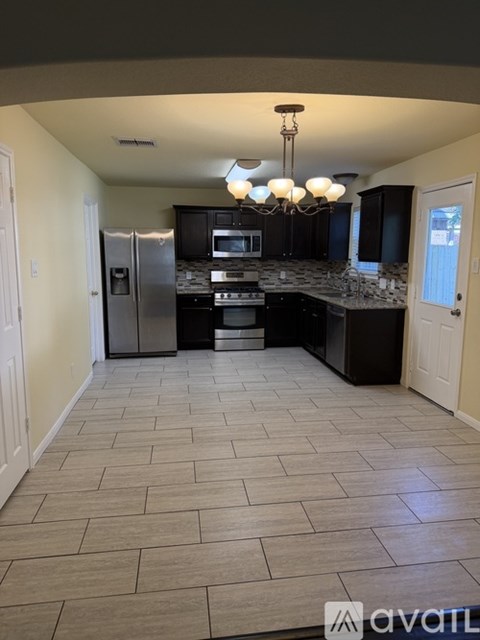 A kitchen with tile flooring and a chandelier.