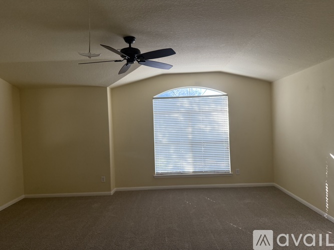 A room with a ceiling fan and a window with blinds.