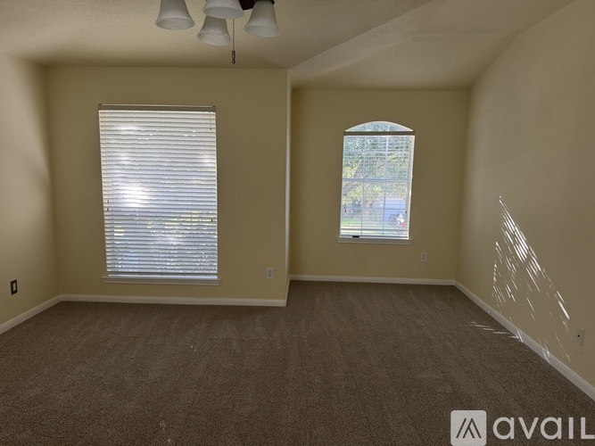 A room with a carpeted floor and two windows.