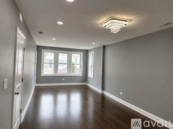 A spacious room with wooden floors and a large window.
