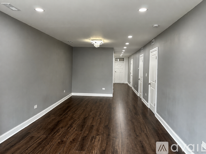 A long, empty hallway with wood floors and white walls.