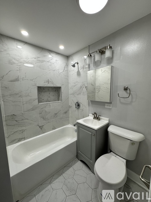 A bathroom with a marble tile wall and a white bathtub.