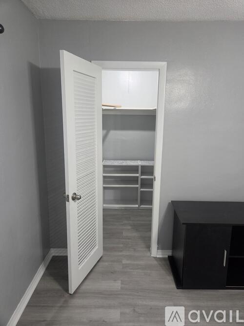 A room with a white door leading to a bedroom.