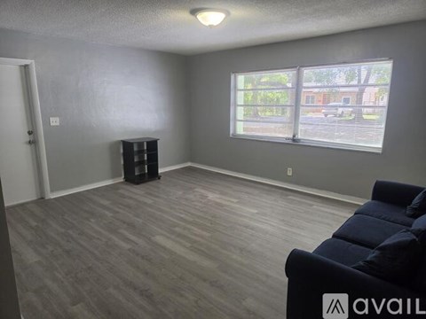 A living room with a dark blue couch and a wooden floor.