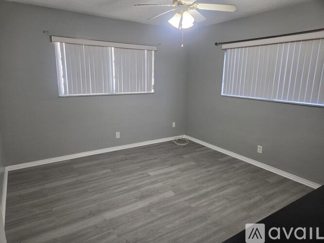 A room with a ceiling fan and two windows with blinds.