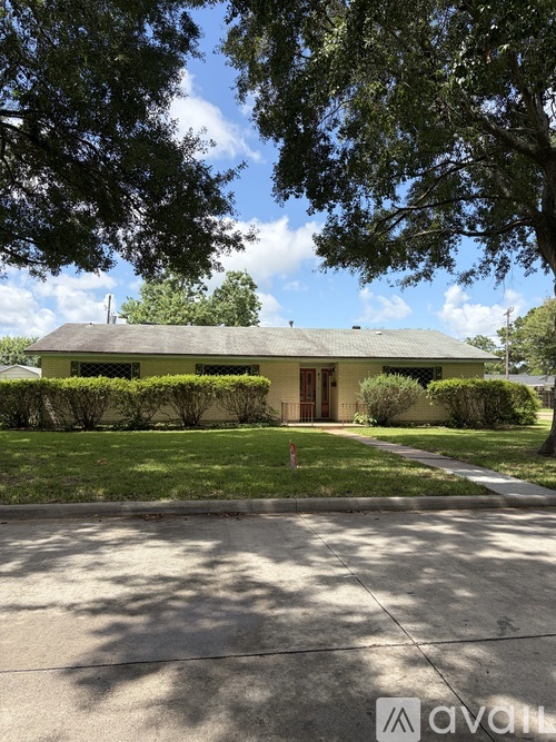A house with a green lawn and trees in front.
