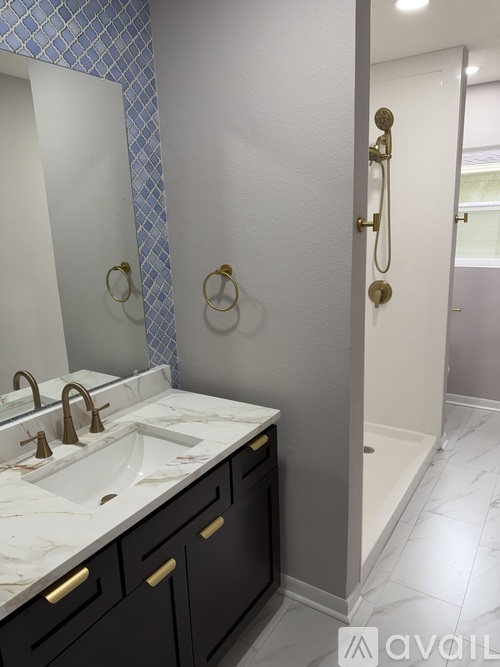 A bathroom with a sink, mirror, and a shower.