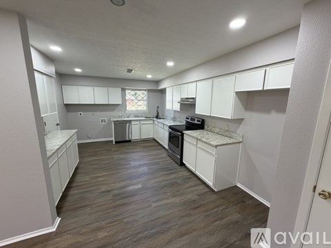 A kitchen with white cabinets and a wooden floor.