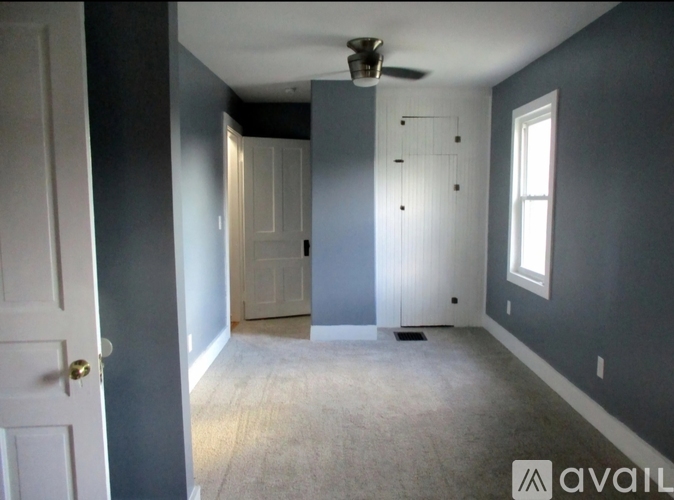 A room with a ceiling fan and a door.