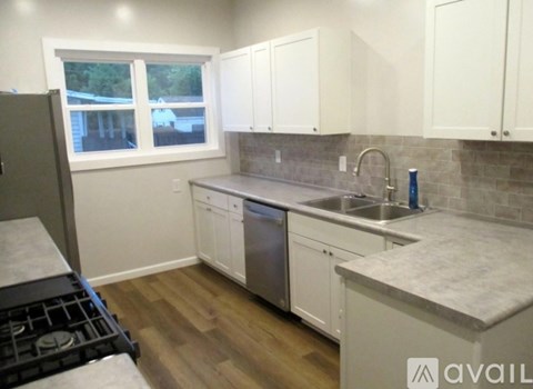 A kitchen with white cabinets and a grey countertop.