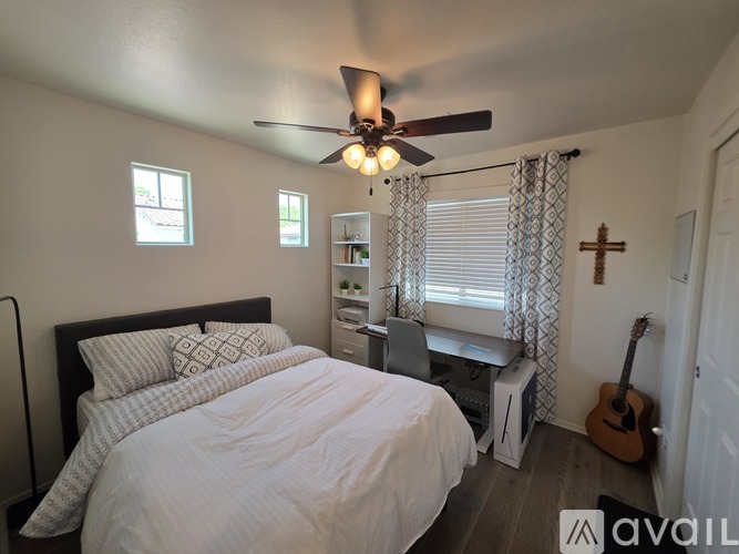 A bedroom with a bed, a guitar, and a window with curtains.