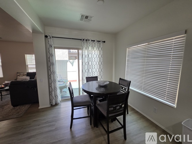 A dining room with a table set for two and a couch in the background.