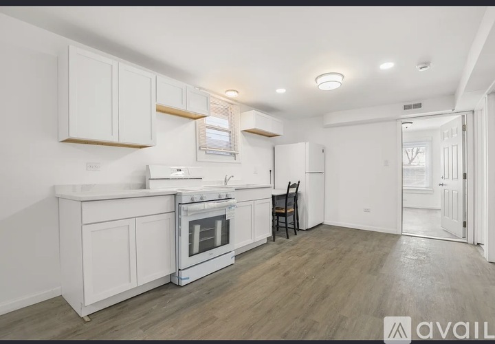A kitchen with white cabinets and a wooden floor.