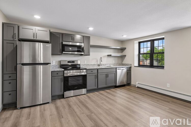A modern kitchen with stainless steel appliances and wooden flooring.