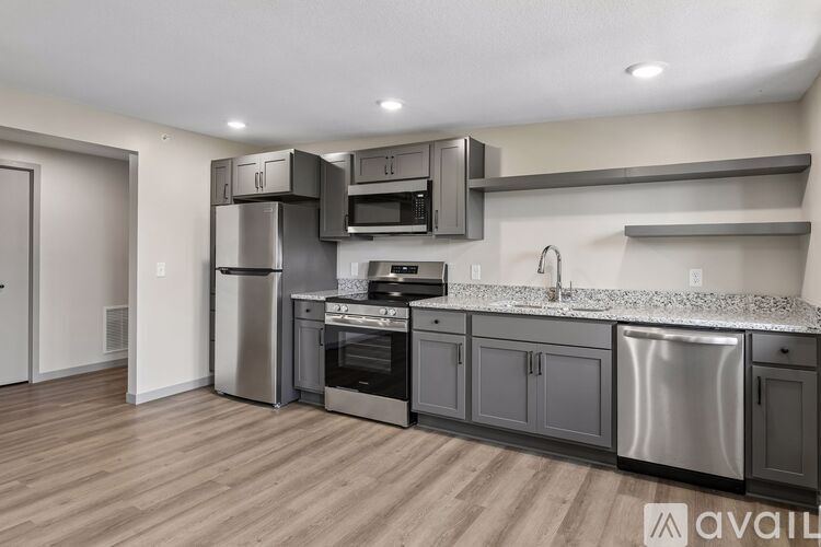 A modern kitchen with stainless steel appliances and wooden flooring.