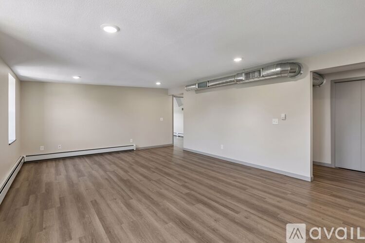 A spacious room with wooden flooring and white walls.