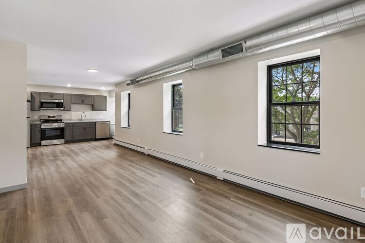 A spacious room with wooden flooring and a window with a view of trees.