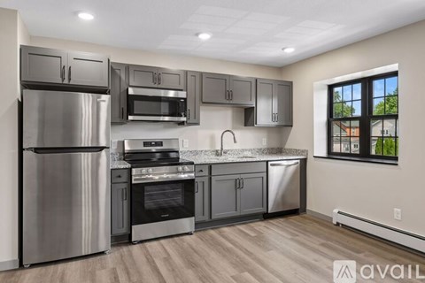 A modern kitchen with stainless steel appliances and wooden flooring.