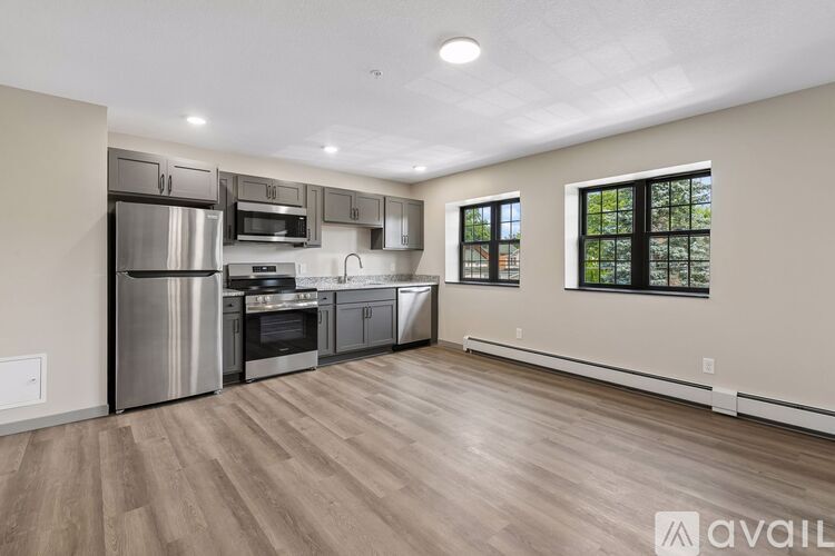 A spacious kitchen with stainless steel appliances and wooden flooring.