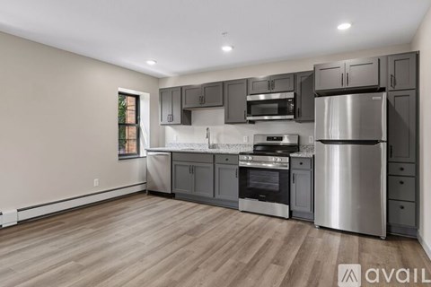 A modern kitchen with stainless steel appliances and wooden flooring.