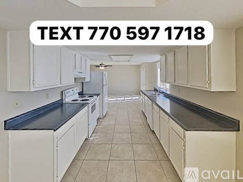 A kitchen with white cabinets and a black countertop is available for rent.