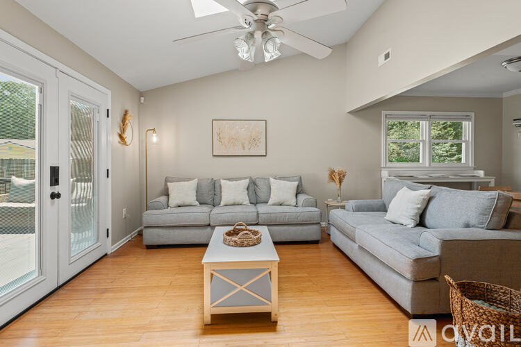 A living room with a grey couch, a coffee table, and a ceiling fan.