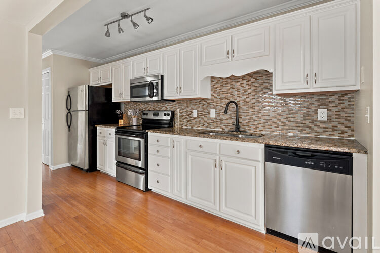 A kitchen with white cabinets and a stone backsplash.