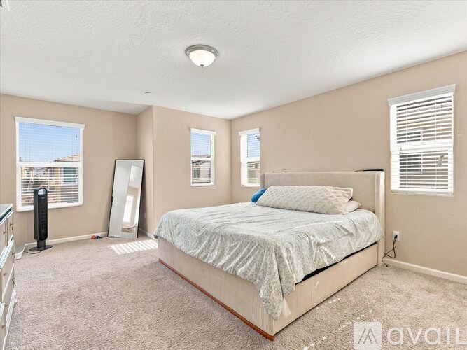 A bedroom with a large bed and a window with blinds.